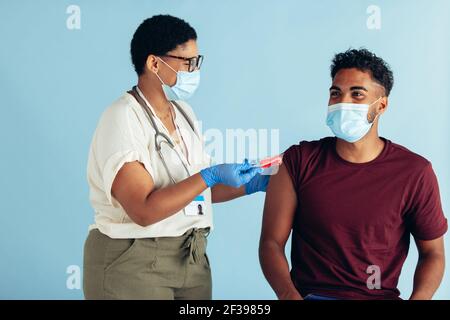Medico femminile che dà una caramella all'uomo dopo la vaccinazione. Uomo ottenere caramelle dal medico dopo aver ottenuto il vaccino covid-19. Foto Stock