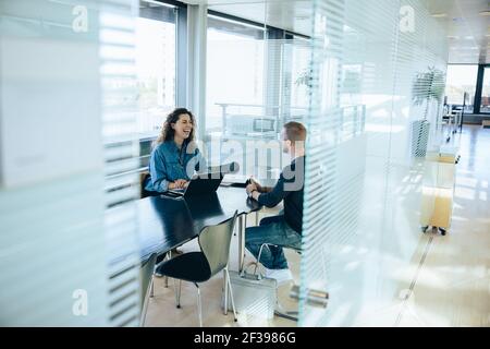 Donna d'affari sorridente che prende l'intervista con un uomo. Colloquio di lavoro nella sala riunioni dell'ufficio. Foto Stock