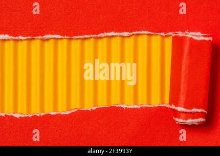 Carta rossa strappata per mostrare il pannello giallo ideale per la copia spazio Foto Stock