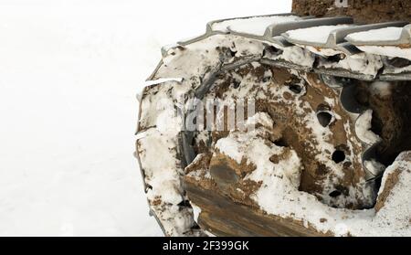 I cingoli metallici di un trattore bulldozer in inverno liberano la strada dalla neve. In una giornata gelida, un bulldozer giallo in inverno. Foto Stock