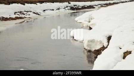 Fiume in primavera, sulla riva della neve. La neve si scioglie con l'arrivo del calore vicino alle rive del fiume. In primavera, il ghiaccio scende il Foto Stock