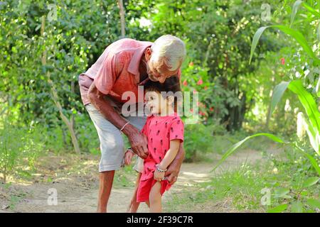 Nonno anziano di origine indiana che innalza con amore il nipote piccolo, india. Concetto per i ricordi dell'Infanzia, sorriso sul volto del bambino piccolo, Foto Stock