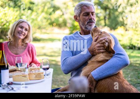 Donna matura sorridente che guarda suo marito che gioca con il cane in cortile Foto Stock