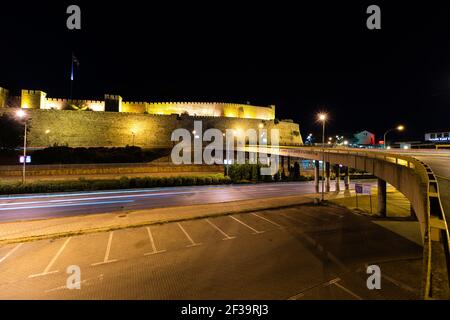 Vista del sentiero leggero del traffico che guida su strada di fronte alla Fortezza di Skopje di notte Foto Stock