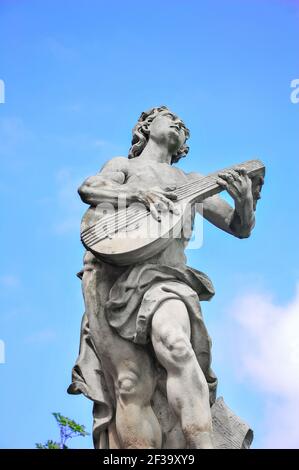 Statua di un musicista che suona un liuto nei giardini del Castello di Książ, Walbrzych, bassa Slesia, Polonia. Figura in marmo silhouette contro il cielo blu Foto Stock