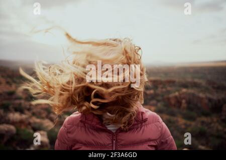 Closeup di giovane donna faccia coperta con i capelli volanti dentro giornata ventosa in montagna Foto Stock