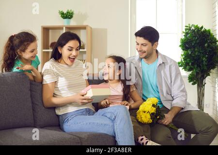 Donna felice ottiene fiori e regali dalla sua famiglia sopra Festa della mamma o della donna Foto Stock