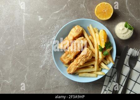 Concetto di cibo gustoso con pesce fritto e patatine tavolo grigio con texture Foto Stock