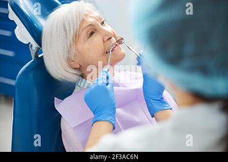 Vecchia persona che ha i suoi denti controllati durante l'esame dentale Foto Stock
