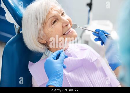 Pensionato sorridente che mostra i denti per l'ispezione dentale Foto Stock
