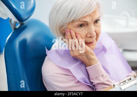 Pensionato interessato con mal di denti che fissano al dentista Foto Stock