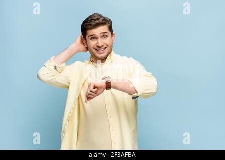 uomo stressato in camicia e con orologio da polso isolato a mano su blu Foto Stock