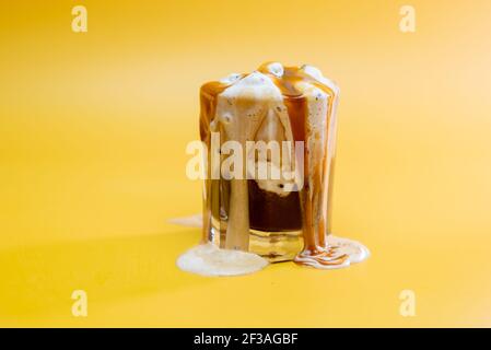 bevanda a base di caffè con marmellata delicata e schiuma che scorre su un sfondo giallo Foto Stock