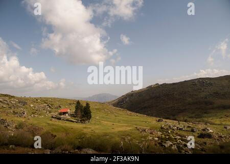 Casa di montagna in un paesaggio di montagna di altopiani e prati con contrasto dalle ombre delle nuvole Foto Stock