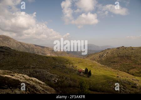 Casa di montagna in un paesaggio di montagna di altopiani e prati con contrasto dalle ombre delle nuvole Foto Stock