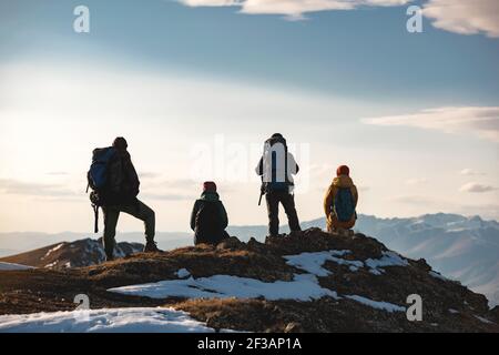 Il gruppo di quattro escursionisti si rilassa sulla cima della montagna. Turisti irriconoscibili con zaini Foto Stock