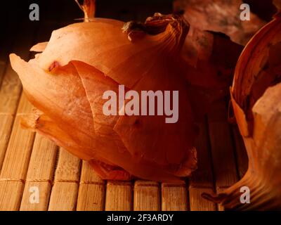 L'uso delle bucce di cipolla in medicina e per colorare le uova di Pasqua. Pelle di cipolla e cipolla su fondo di legno. Foto Stock