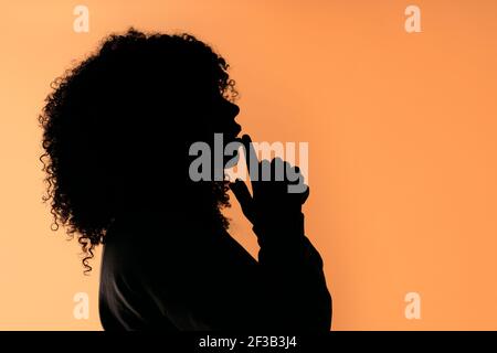 Foto di scorta di una donna afro sicura e non riconosciuta con le mani insieme su sfondo marrone in studio. Foto Stock