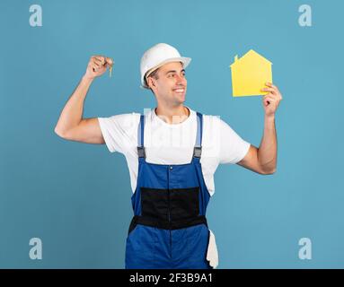 Buon Handycam in tuta e Hardhat chiavi di tenuta e carta Personaggio della casa Foto Stock