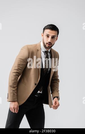 giovane uomo musulmano in abiti eleganti guardando telecamera isolata su grigio Foto Stock