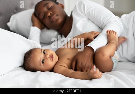 Carino bambino afroamericano dormire a letto con mamma Foto Stock