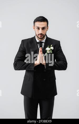 Groom arabo con le mani che pregano guardando la telecamera isolata grigio Foto Stock