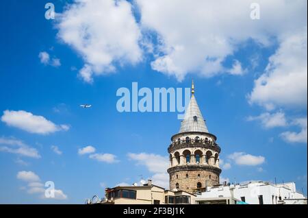 Istanbul, Turchia - Settembre, 2018: Vista della Torre Galata o Galata Kulesi in giornata di sole con cielo blu nuvoloso con aereo in volo. Vista dal tetto Foto Stock