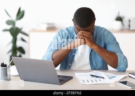 Depresso imprenditore afro-americano che ha problemi al lavoro Foto Stock