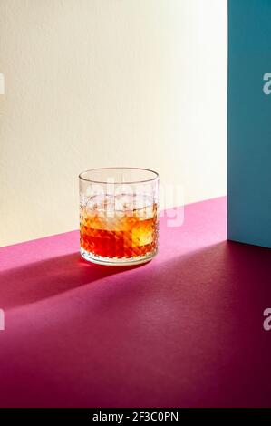 Vetro con Whiskey e Ice Cube sul tavolo con ombre dure. Moderno stile isometrico. Concetto creativo. Foto Stock