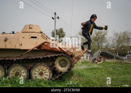 Halabja, Iraq. 16 Marzo 2021. Un bambino che visita il monumento di Halabja gioca sulla cima di un veicolo militare che è stato usato nell'attacco chimico effettuato dal governo iracheno il 16 marzo 1988 durante i giorni di chiusura della guerra Iran·Iraq nella città curda di Halabja, che ha ucciso quasi 5000 persone e ha ferito circa 10000 persone, la maggior parte erano civili. Credit: Ismael Adnan/dpa/Alamy Live News Foto Stock