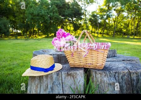 Bel cesto con fiori e cappello si erge su un legno moncone Foto Stock