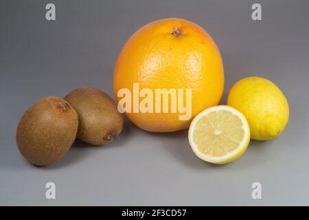 Frutta invernale, pompelmo, kiwi e limoni su sfondo grigio Foto Stock