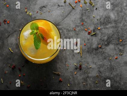 Cocktail di pesca con ghiaccio e alcune foglie di menta. Vista dall'alto. Su sfondo scuro Foto Stock