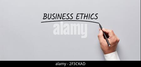 Mano di uomo d'affari che sottolinea la parola etica aziendale su sfondo grigio. Evidenziare l'etica del business. Foto Stock