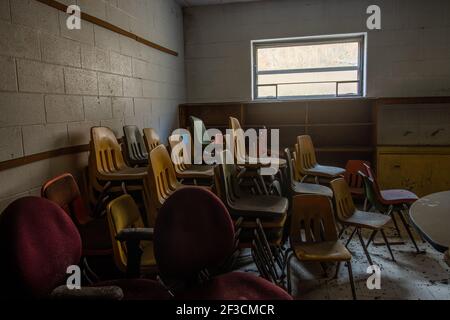 Le sedie vecchie sono accatastate nell'angolo di un'aula abbandonata in Appalachian Kentucky. Foto Stock