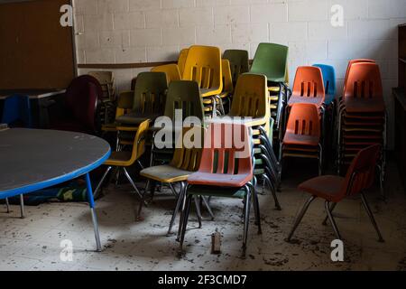 Le sedie vecchie sono accatastate nell'angolo di un'aula abbandonata in Appalachian Kentucky. Foto Stock