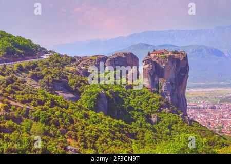 Meteora, Grecia, Monastero della Santissima Trinità sulla cima della scogliera e Kalampaka città nella valle, vista del tramonto Foto Stock