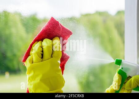 Finestre di lavaggio. Giovane donna in guanti di gomma gialla strofina il bicchiere. Concetto di casalinghi. Foto Stock