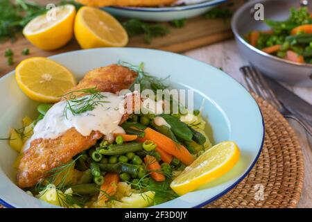 pesce impanato con verdure su un piatto Foto Stock