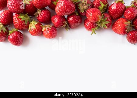 Fragole su sfondo bianco. Primo piano delle bacche mature. Fragole al bordo dell'immagine con spazio per la copia. Vista dall'alto. Sfondo di bacche rosse. Backgro Foto Stock