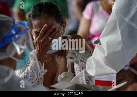 16 marzo 2021, Gianyar, Bali, Indonesia: Una donna vista mentre chiude il viso con la mano durante la vaccinazione. Una vaccinazione di massa del Covid-19 verso i cittadini tenuta nel Grande Palazzo di Ubud, come fase del programma della zona Verde a Bali. Il programma della zona verde coinvolge tre regioni a Bali; Ubud, Sanur e Nusa Dua, sono pronti a preparare un piano di riapertura internazionale del turismo, che rientra nel focolaio. (Immagine di credito: © Dicky Bisinglasi/ZUMA Wire) Foto Stock