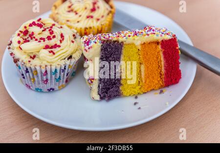 Pan di Spagna a strati arcobaleno e cupcakes con crema di burro Foto Stock