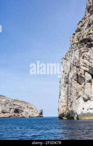 Litorale che guarda verso una grande scogliera a faccia dal mare. La posizione è Parco Nazionale Regionale di Porte Conte, Alghero Sardegna. Foto Stock