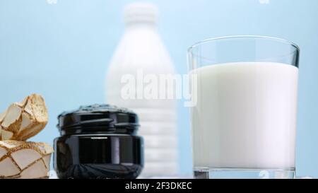 Latte fresco in un bicchiere con pasticceria e marmellata, latte su legno, ancora vita con i latticini. Foto Stock