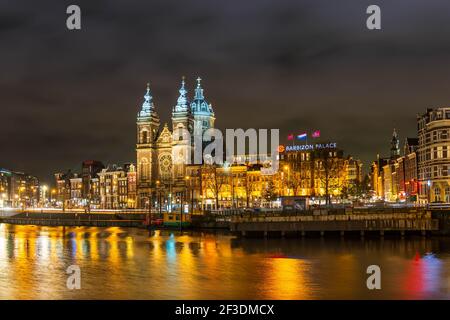 La banchina di Prins Hendrikkade e la Basilica di San Nicola ad Amsterdam di notte in Olanda, Paesi Bassi Foto Stock