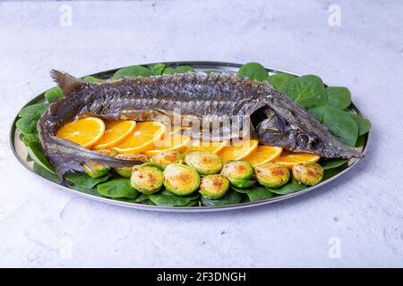 Sterlet al forno (storione) con spinaci, arance e germogli di Bruxelles. Cucina russa. Primo piano. Foto Stock