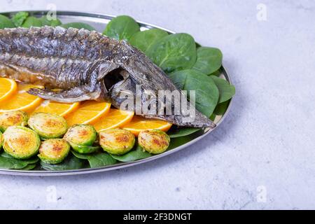 Sterlet al forno (storione) con spinaci, arance e germogli di Bruxelles. Cucina russa. Primo piano. Foto Stock