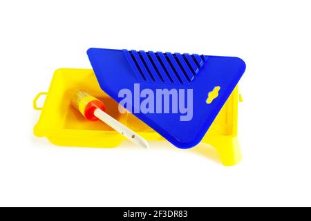 Spatola in plastica blu per carta da parati. Cuvetta per vernice gialla. Primo piano. Isolato su sfondo bianco. Foto Stock