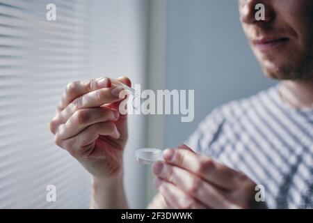 Custodia per lenti a contatto con apertura uomo giovane. Temi vista e routine quotidiana. Foto Stock