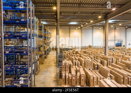 Interni logistici del magazzino con scaffalature e confezioni sottili in piedi sul pavimento del negozio. Concetto di trasporto e logistica. Foto Stock